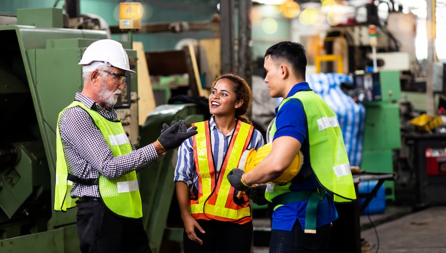 Three construction workers talking in an industrial warehouse